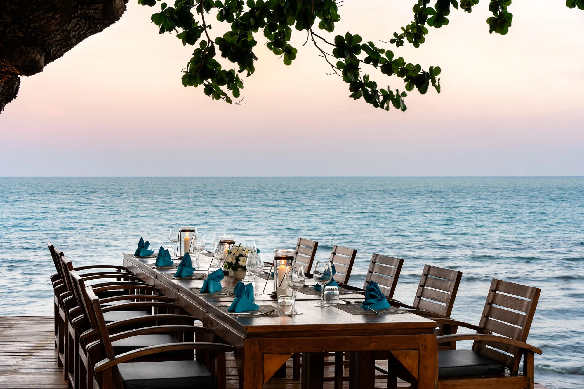 Long table set on the deck over the water at sunset